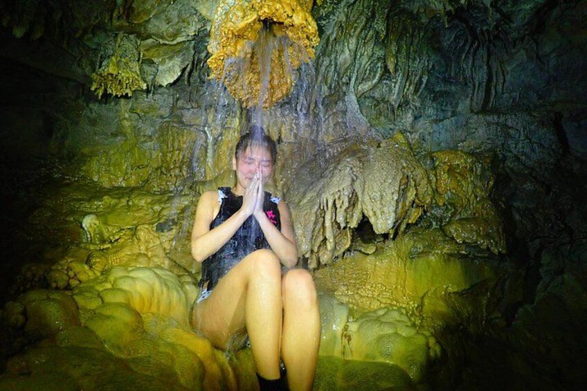 A person sitting in a cave with stalactites and stalagmites. 4