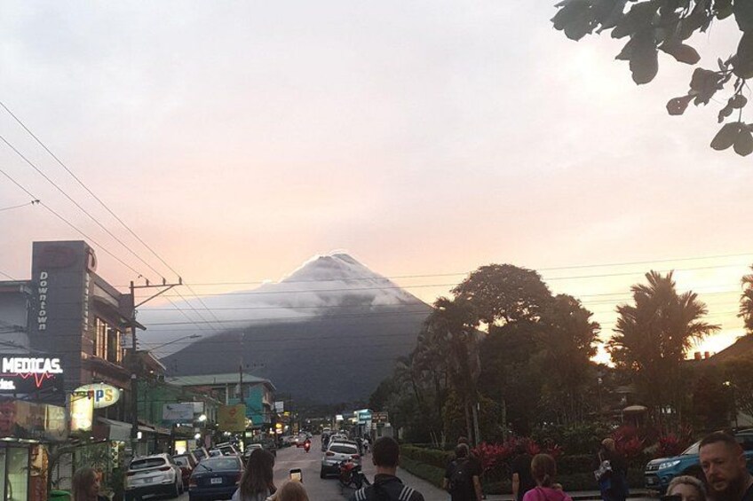A busy street with cars and pedestrians, a mountain in the background, and buildings with signs. 3