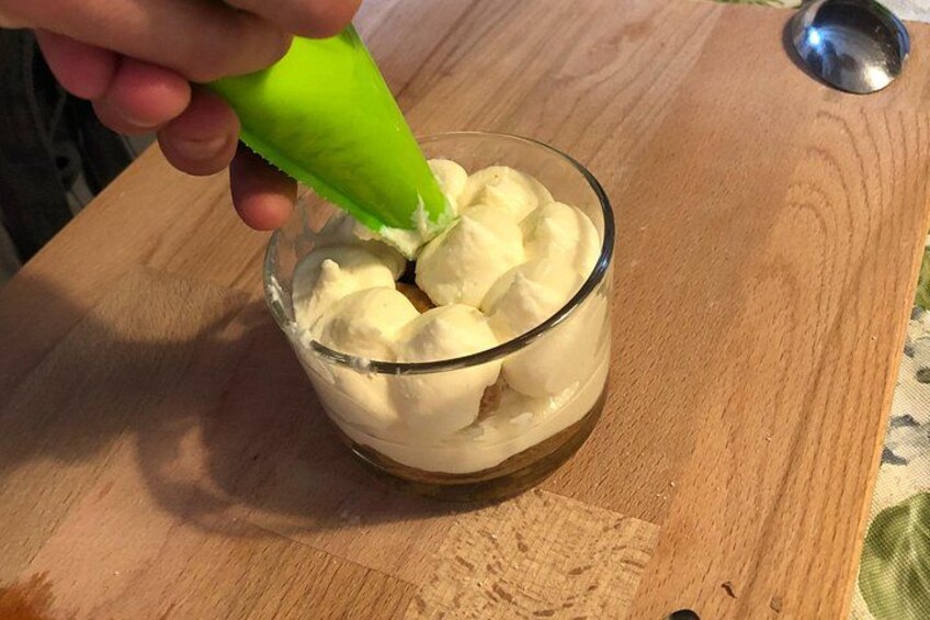 En hånd presser en grøn flaske ud i en glasskål med flødeskum. 4