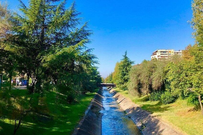 Un étroit canal bordé d’arbres, avec un bâtiment visible au loin. 4