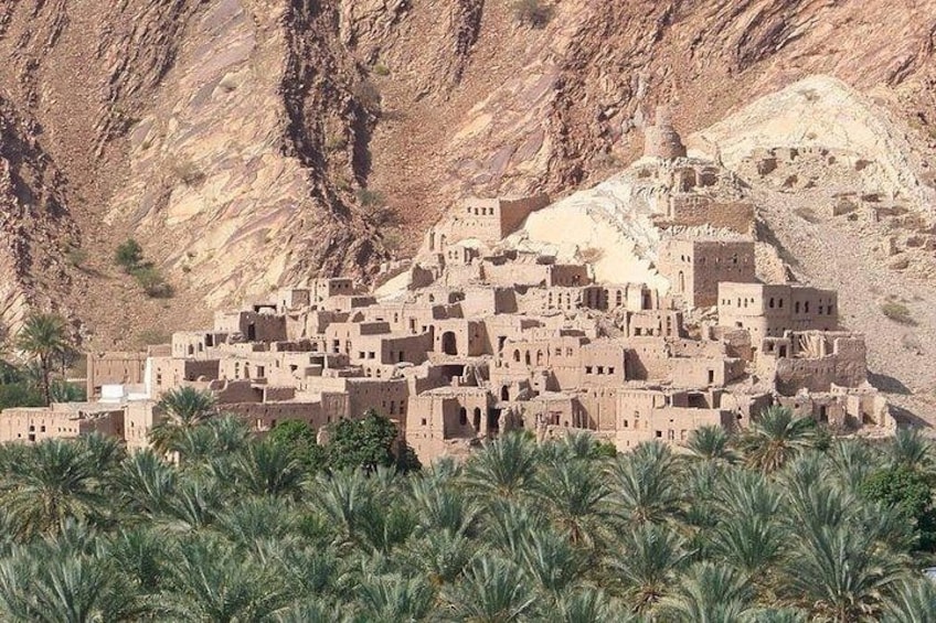 A desert village with adobe structures, palm trees, and rocky mountains in the background. 5