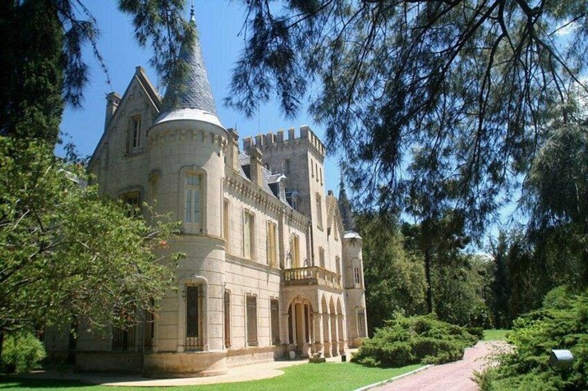A large, historic stone building with a turret, surrounded by lush greenery and a well-maintained lawn. 5