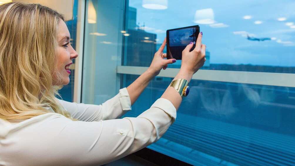 woman taking a photo with her phone inside the Aspire airport Lounge