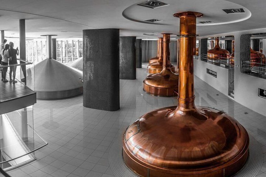 A modern interior with large copper vessels, reflective surfaces, and a geometric structure. 4