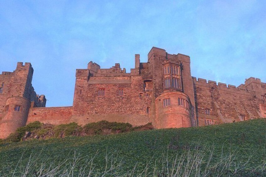 A historic stone castle with battlements, a turret, and a grassy foreground. 5