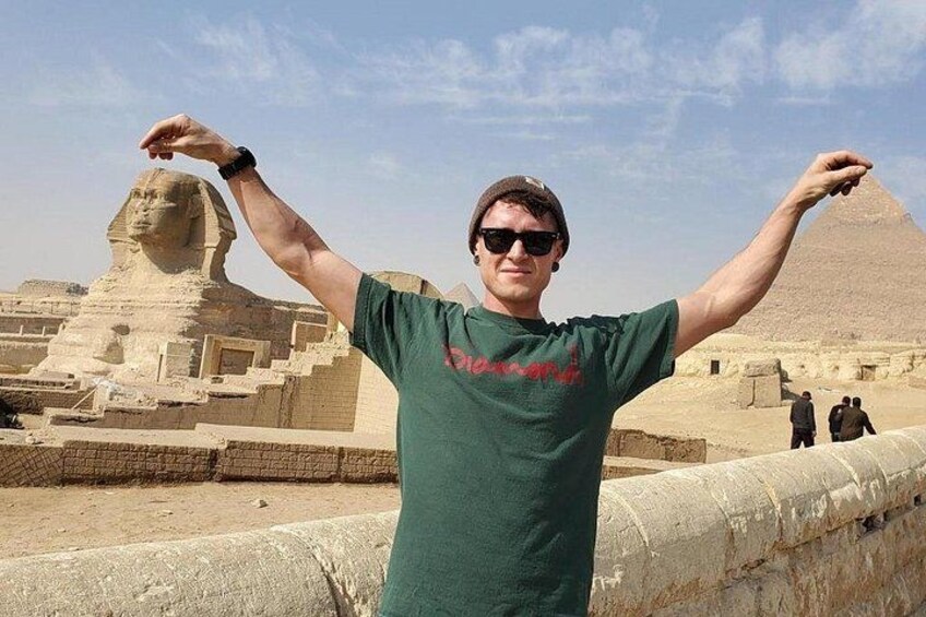 Une personne se tient devant le Grand Sphinx, les bras levés, et porte un t-shirt vert. 5