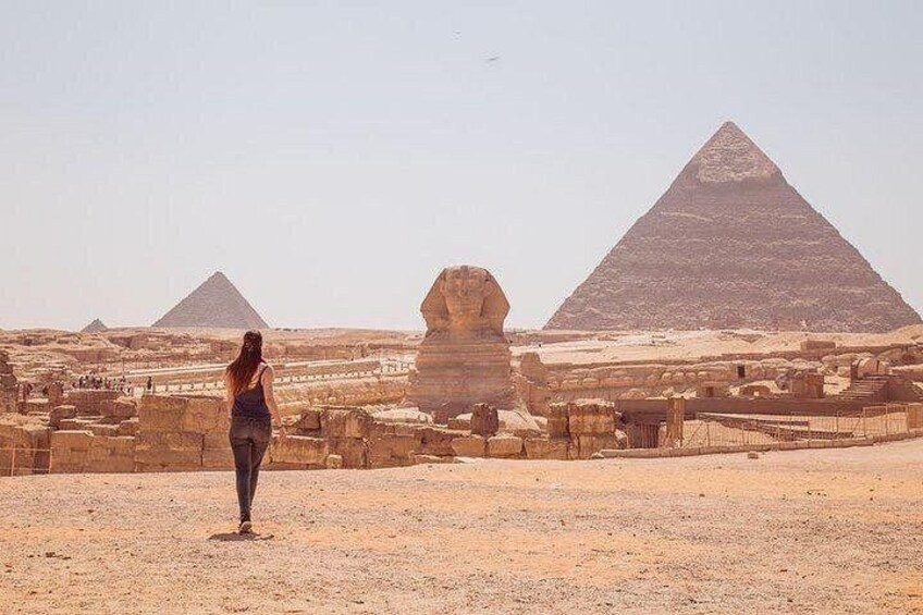 Une personne se tient debout dans un désert, avec des pyramides en arrière-plan. 4