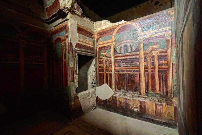 A room with a partially damaged wall featuring classical architectural elements. 3