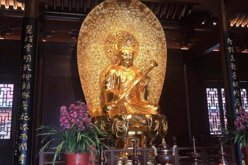 A golden statue of a seated figure with intricate patterns, surrounded by potted plants and traditional Chinese architecture. 3