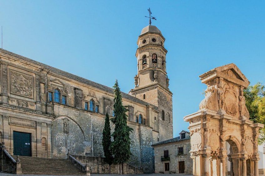 Un edificio histórico con una torre de campanas, una escalera que conduce a la entrada y un monumento escultórico. 4