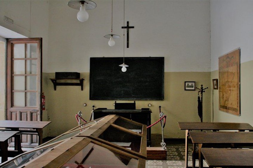 Un aula con una pizarra, mesas de madera y un amplio ventanal. 5