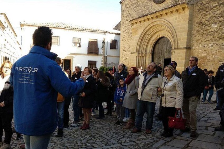 Un grupo de personas reunidas en una calle adoquinada con edificios históricos, incluyendo una iglesia con un arco de entrada redondeado. 2