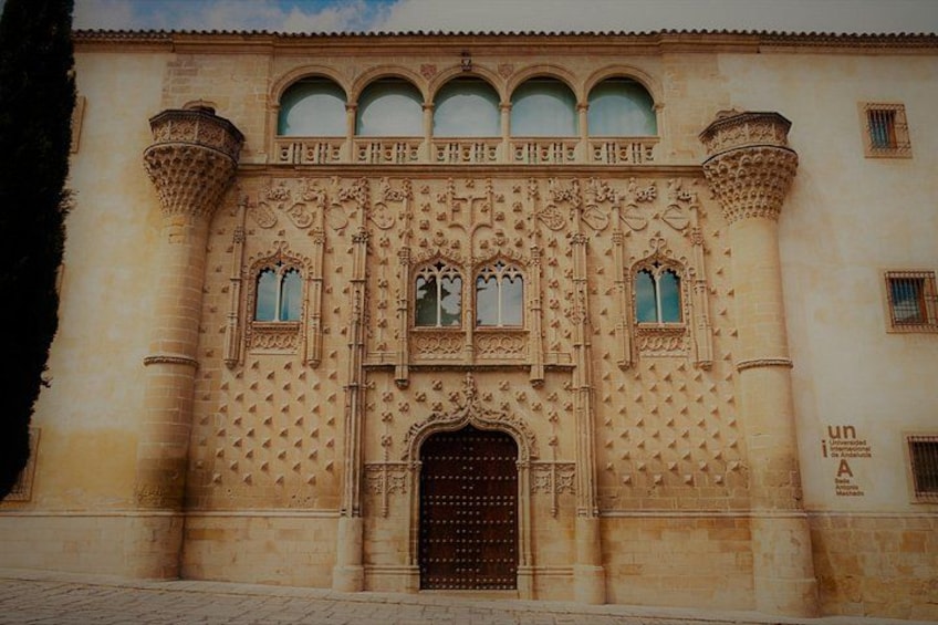 Un edificio histórico con elaboradas esculturas, un amplio arco central y una serie de ventanas en arco en la parte superior. 3