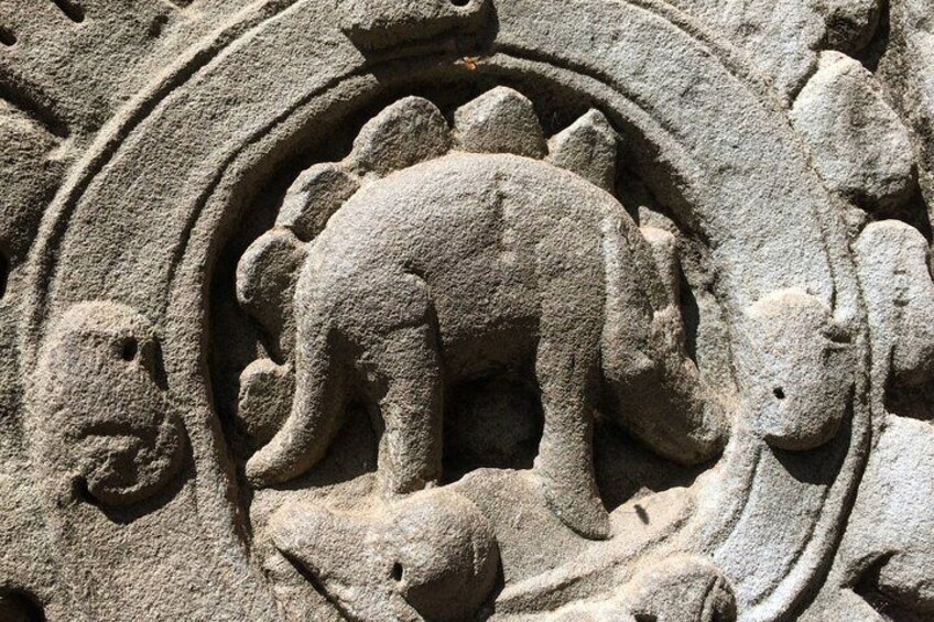 A stone carving of a dinosaur with a circular pattern around it. 4