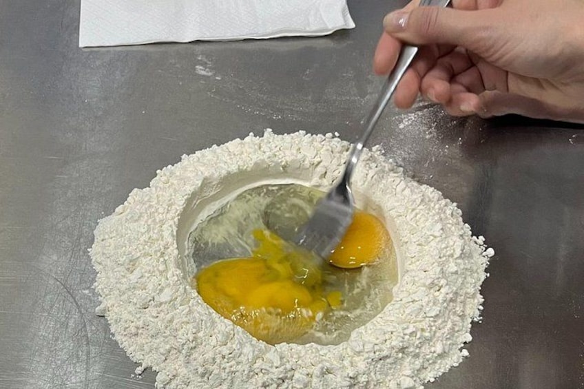 A person mixing eggs and flour in a bowl. 2