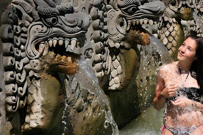 A person interacting with a water feature in front of a dragon sculpture. 2