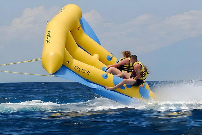 A yellow and blue inflatable watercraft with two people wearing life jackets, floating on the ocean. 3