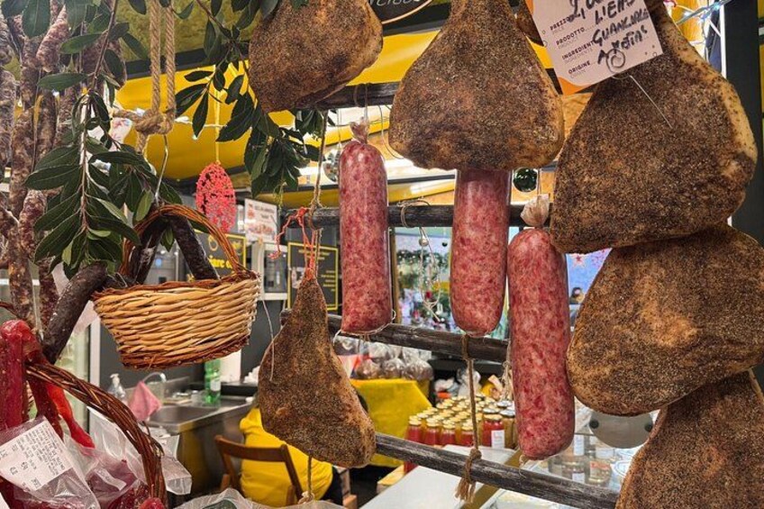 Various types of cured meats hanging in a market. 5