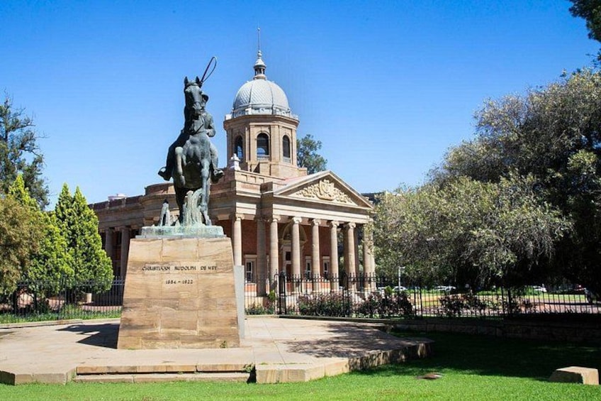 A statue of a man on horseback in front of a neoclassical building with columns and a dome. 1