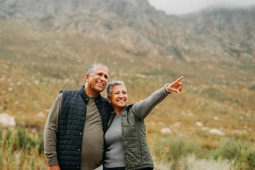 Two people standing outdoors with a mountainous landscape in the background. 4