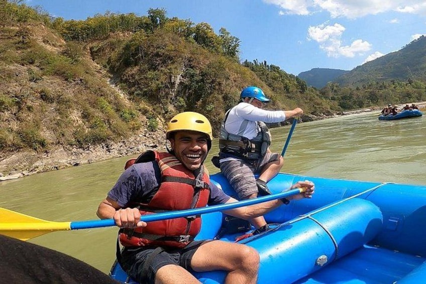 Deux personnes dans un radeau bleu sur une rivière, portant des gilets de sauvetage et des casques, et pagayant. 5