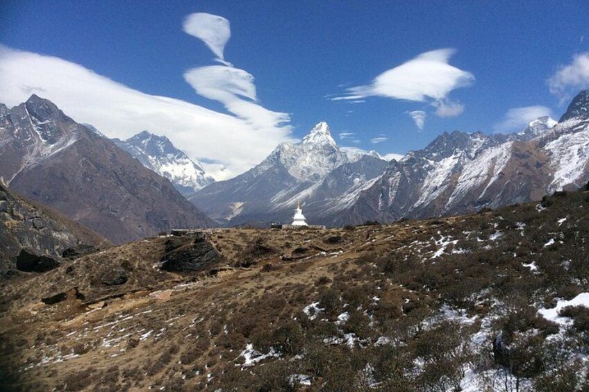 A mountainous landscape with snow-capped peaks, a rocky foreground, and a white structure in the distance. 5
