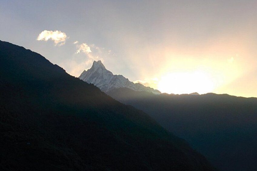 A mountain range with a prominent peak and a setting sun. 2