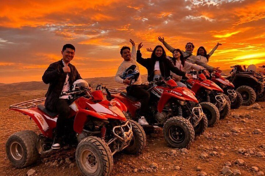 A group of people on quad bikes in a desert landscape during sunset. 3