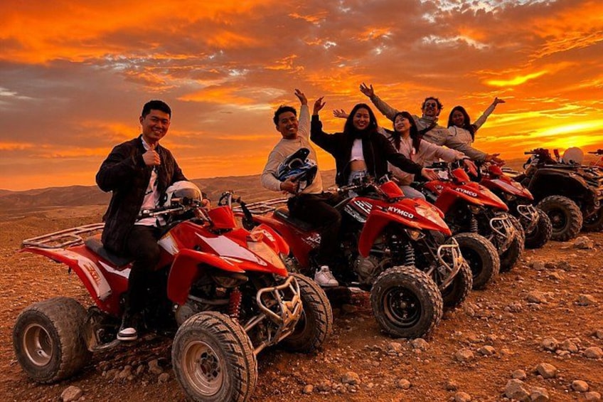 A group of people on quad bikes in a desert landscape during sunset. 3