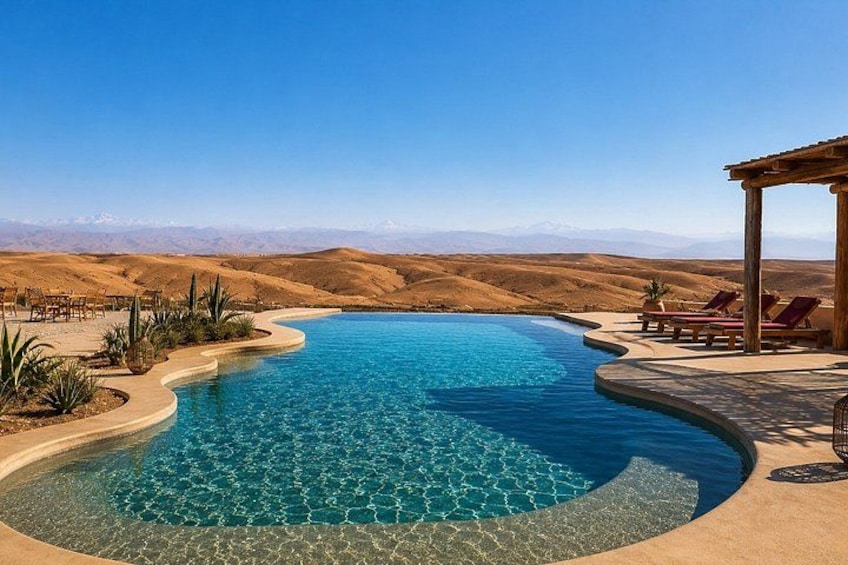 A swimming pool with a curved design, surrounded by desert landscape and mountains in the background. 2