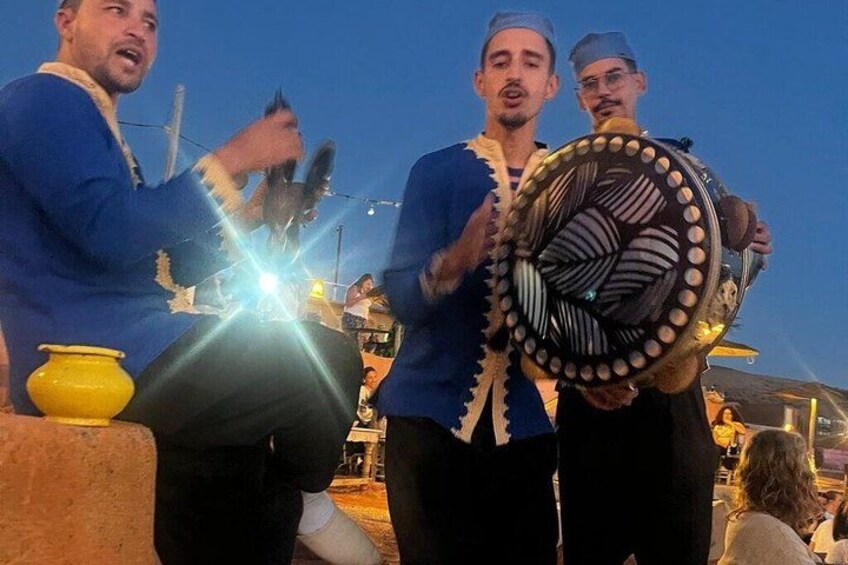 Three people in blue traditional attire holding a decorative fan. 3