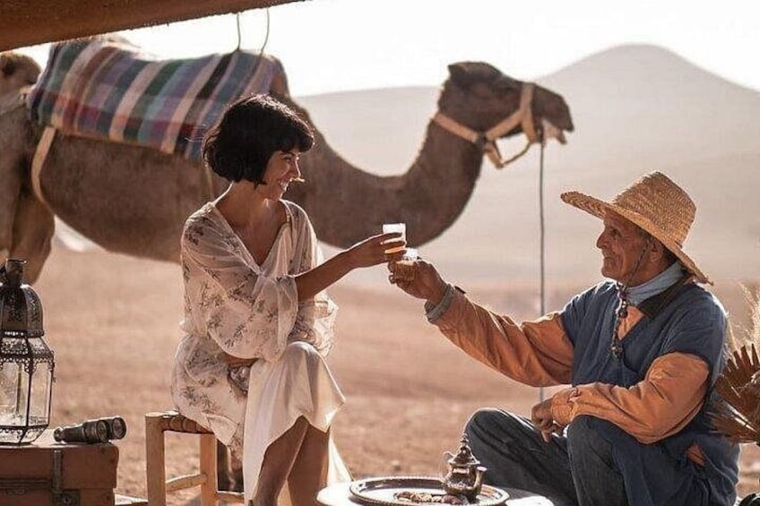 A desert landscape with a camel and a person in traditional attire. 1