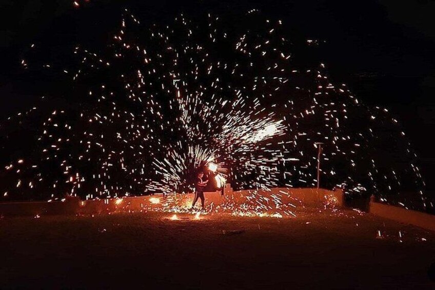A person standing in a field with sparks flying from a device on the ground. 3