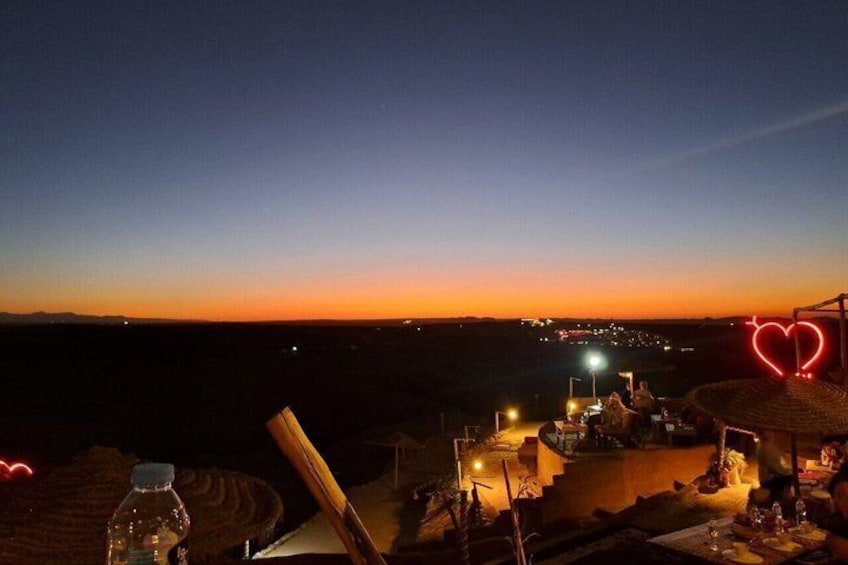 A sunset view from a terrace overlooking a beach with a heart-shaped light decoration. 2
