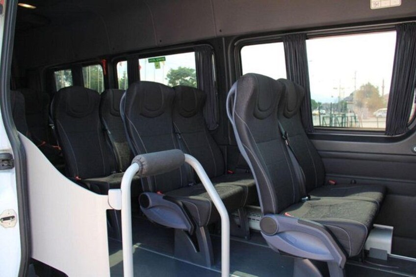 A bus interior with rows of seats and a bench seat. 3