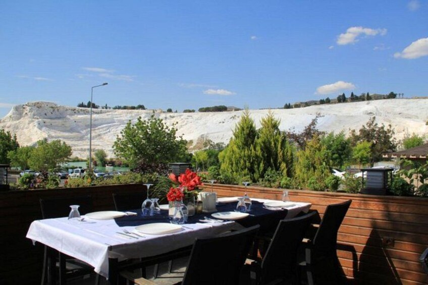 An outdoor dining area with a table set for two, overlooking a rocky landscape. 2