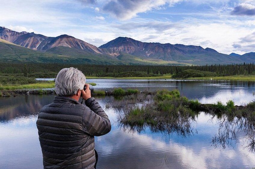 Una persona fotografiando un lago con montañas al fondo. 3