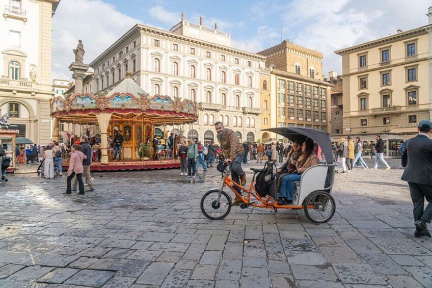A cobblestone square with a carousel, a horse-drawn carriage, and historic buildings. 3