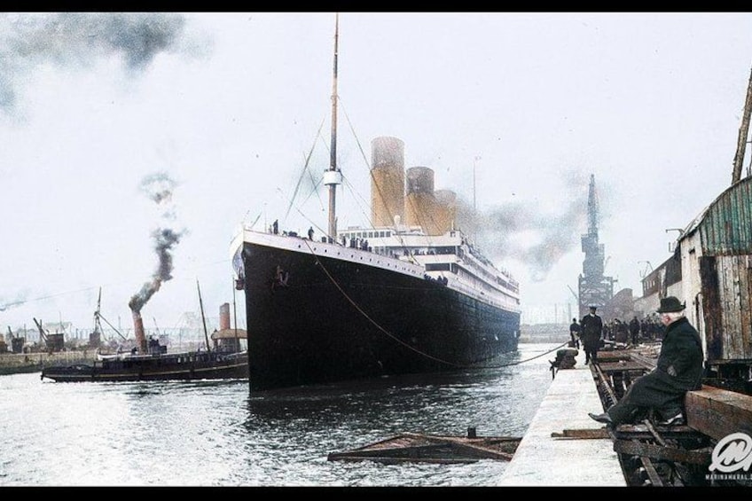A large ship docked at a port with industrial buildings in the background. 1