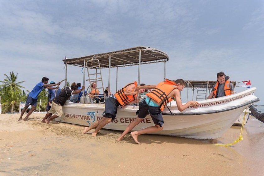 Un groupe de personnes poussant un bateau sur une plage de sable. 2