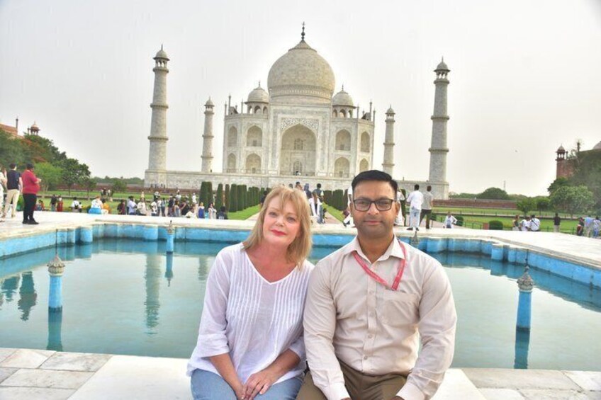 Two people sitting by a pool with the Taj Mahal in the background. 4