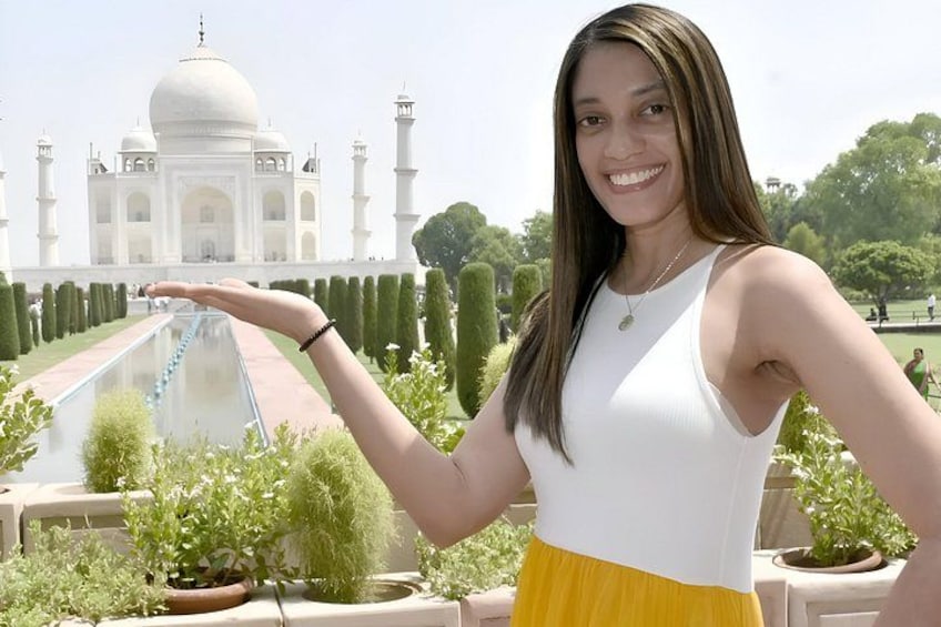 A person in front of the Taj Mahal with a garden path and trees. 5
