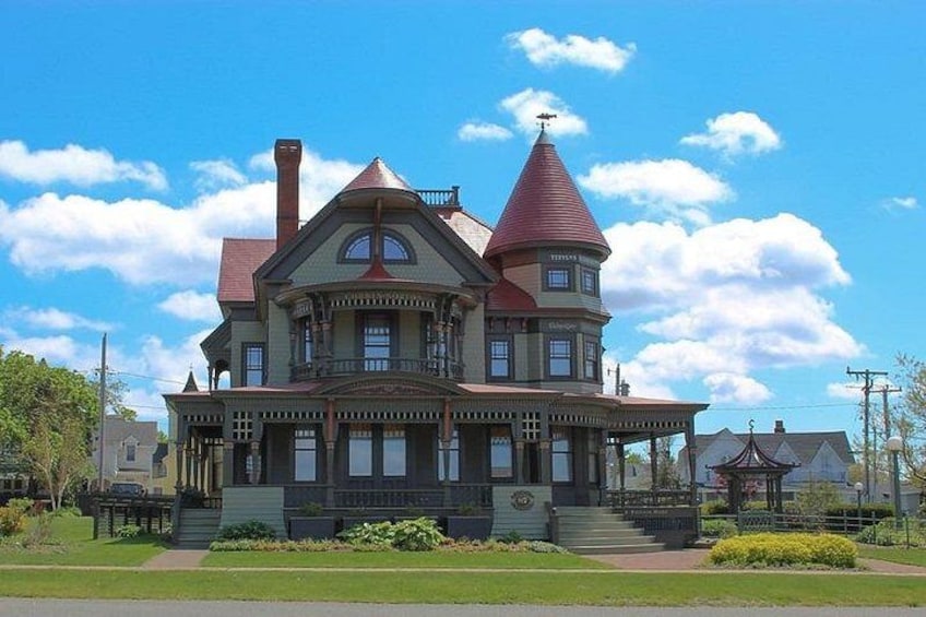 Una amplia y ornamentada casa de estilo victoriano con techo rojo y múltiples chimeneas. 3