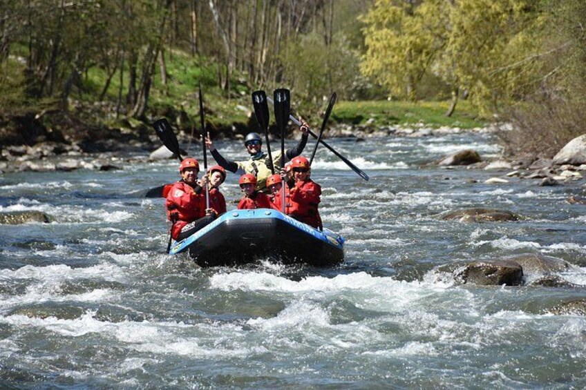 A group of people in a raft navigating a river surrounded by trees. 2