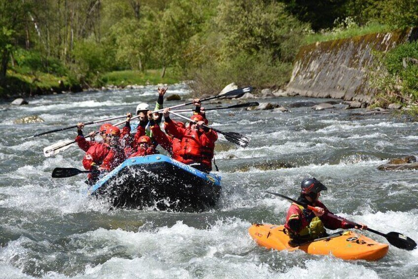 A group of people in a blue raft and an orange kayak navigating a river. 5