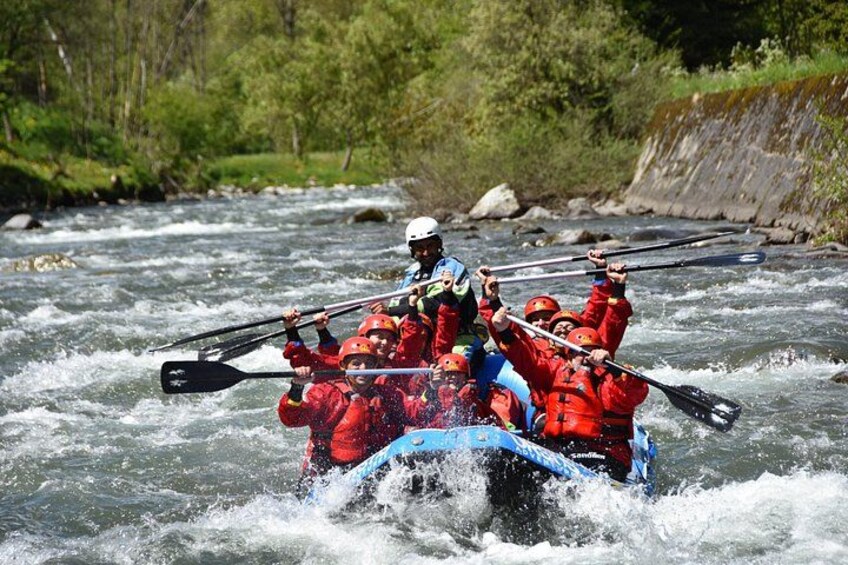 A group of people in red jackets paddling a blue raft on a river. 5