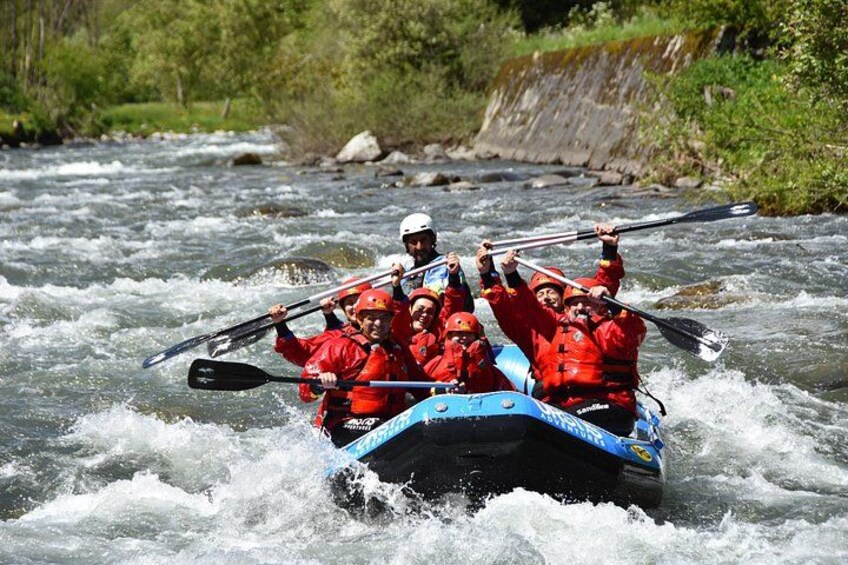 A group of people in a blue raft navigating a river. 1