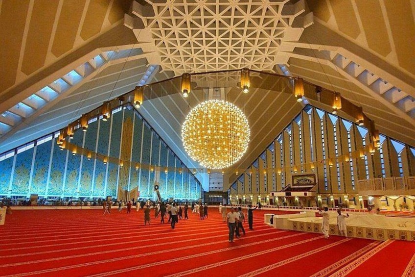 A large indoor space with a red carpet, high ceilings, and a prominent spherical light fixture. 1