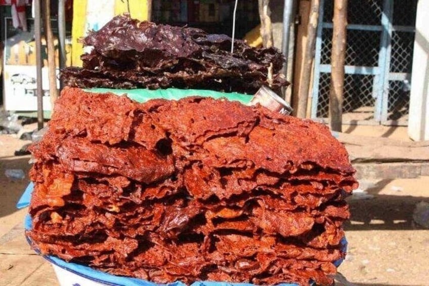 A large stack of red food items, possibly dried meat, on a blue plate. 1