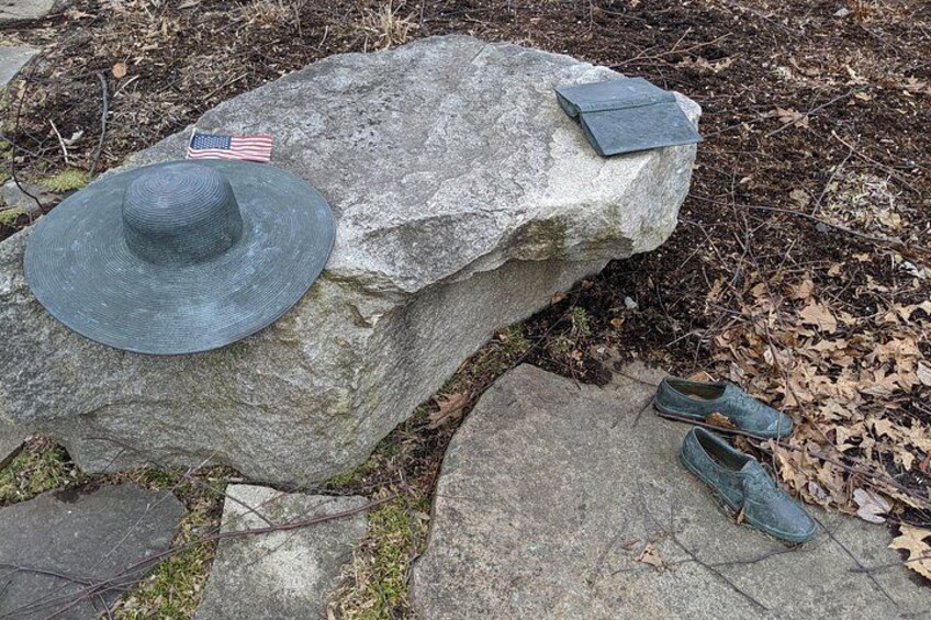 A large rock with a hat, a flag, and a book on top. 2